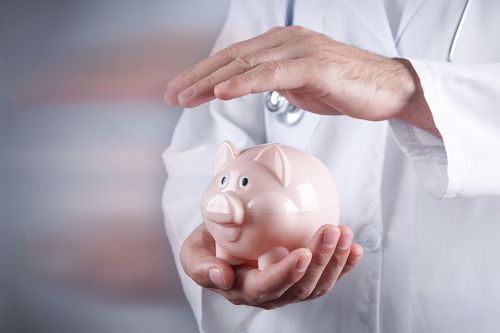 Foto: Arzt hält Hand über Sparschwein